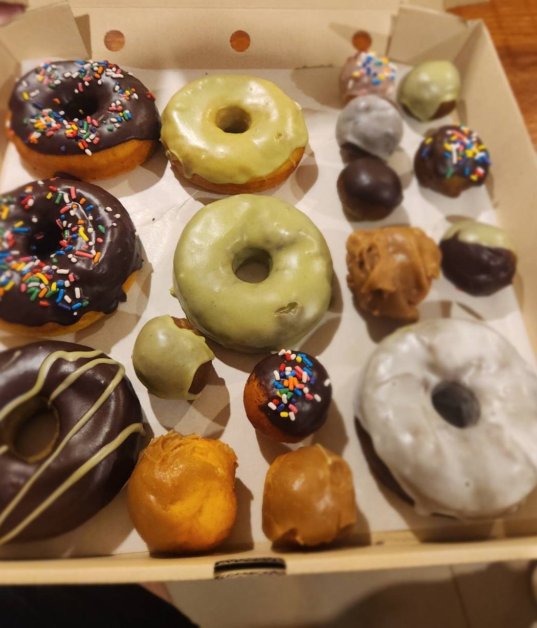 An assortment of glazed and sprinkle-topped donuts and donut holes